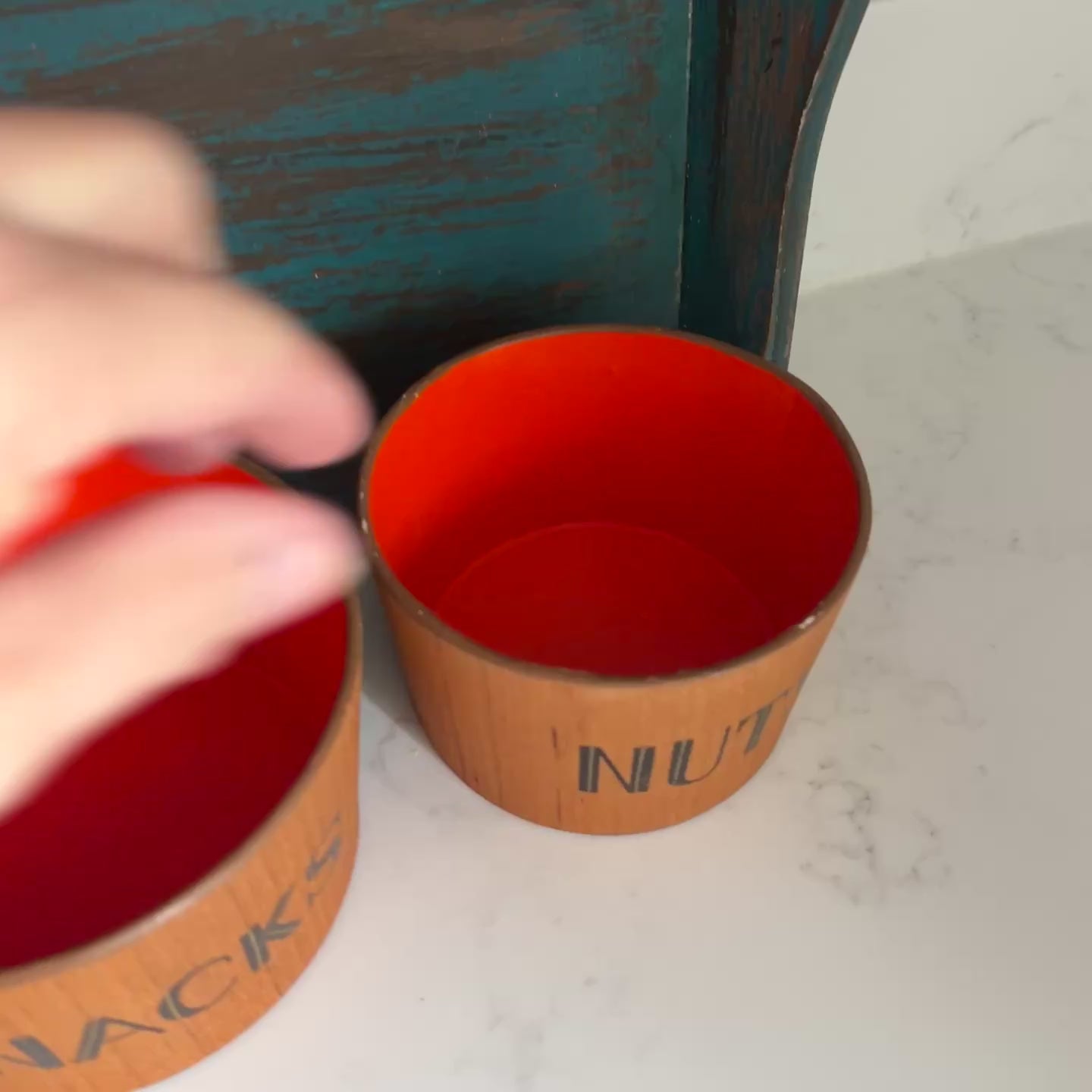 Video of teak snack bowl set with bold orange interior blue tray on white marble