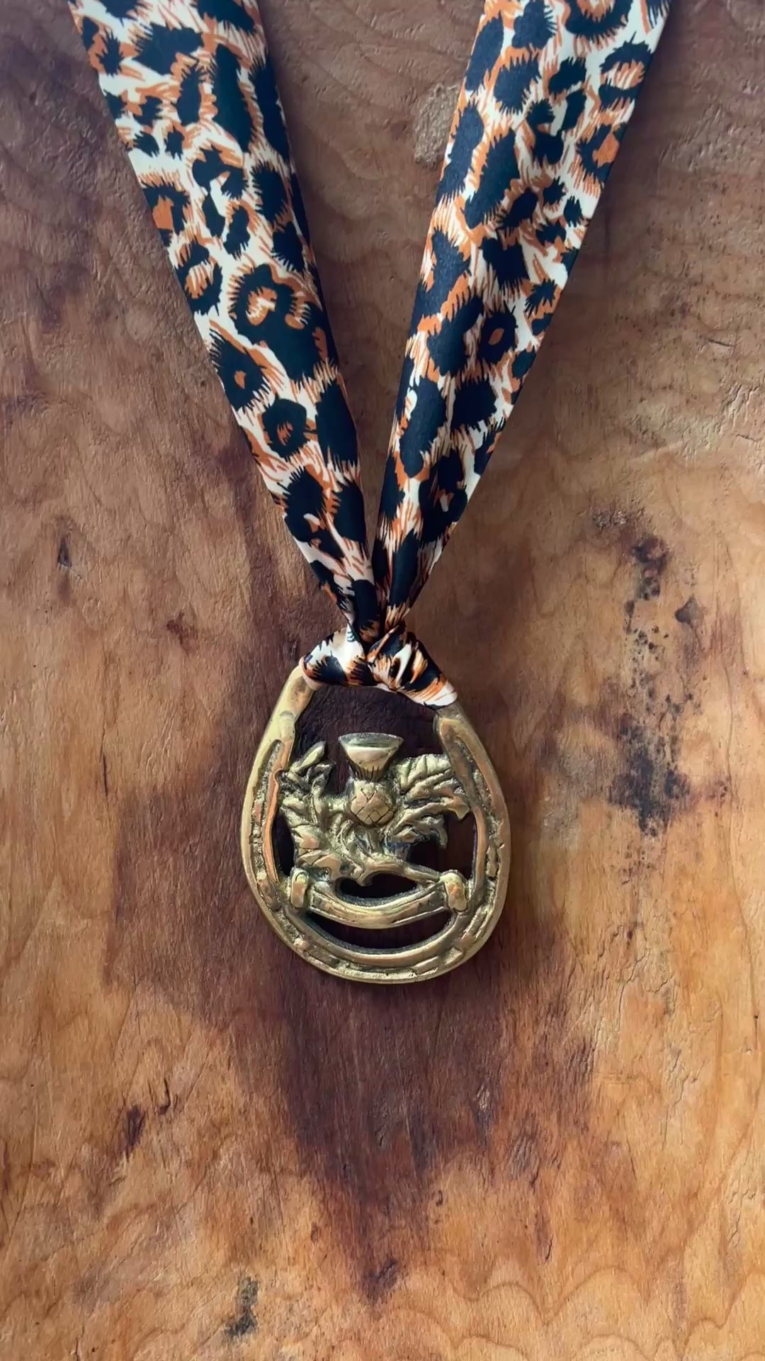 Video ofVintage brass Scottish thistle medallion necklace with leopard-print scarf, rustic boho jewelry.