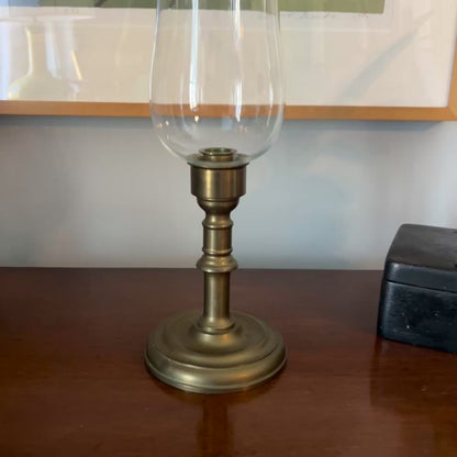 video of Brass candlestick with a clear glass holder on a wooden surface