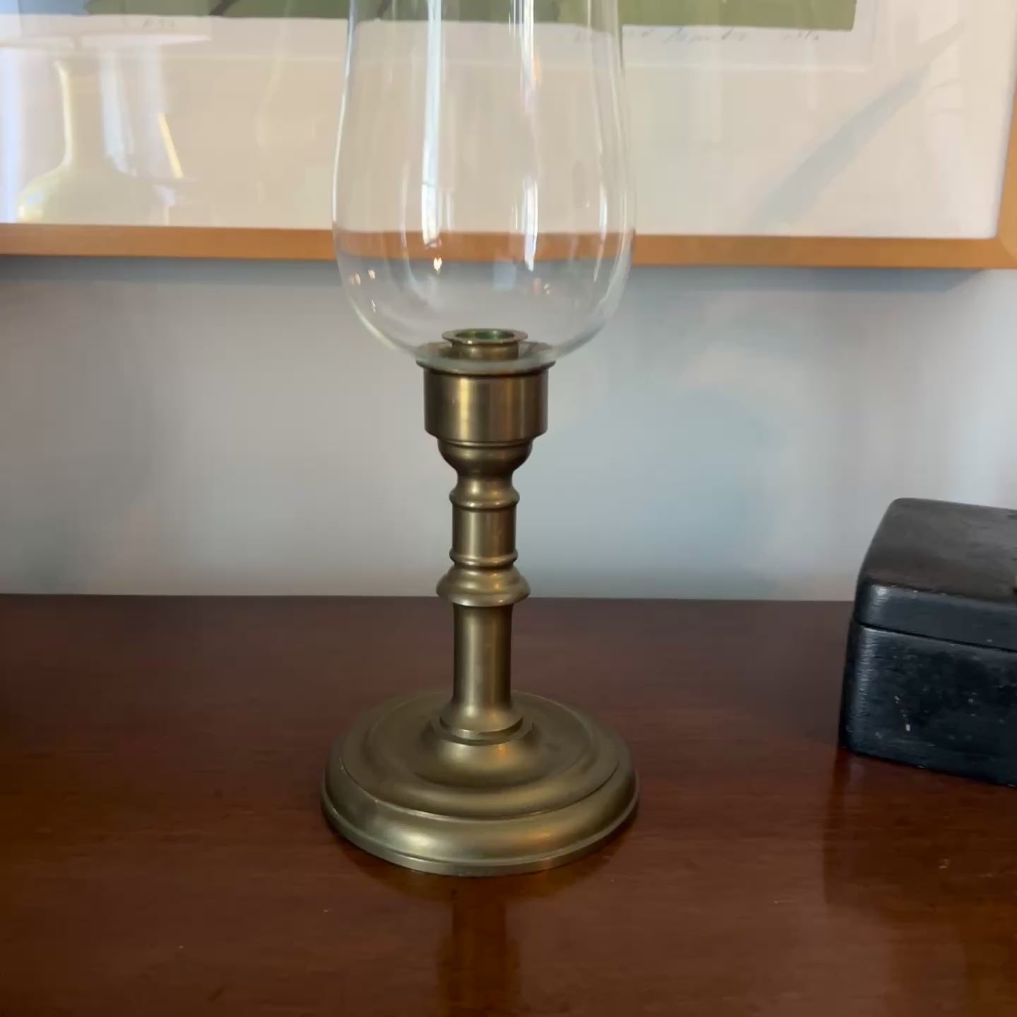 video of Brass candlestick with a clear glass holder on a wooden surface