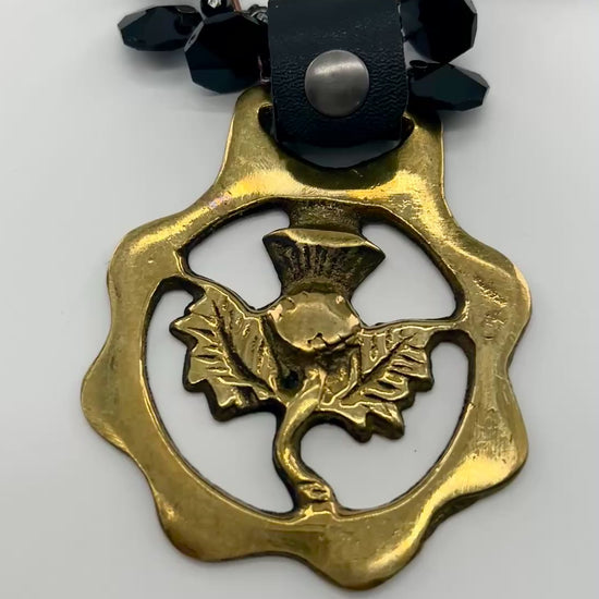 video of Black beaded necklace with brass medallion with leather attachment  with white background