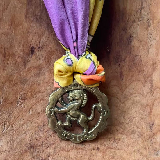 Video of Vintage Red Lion London brass medallion necklace with bright retro floral scarf on wooden surface
