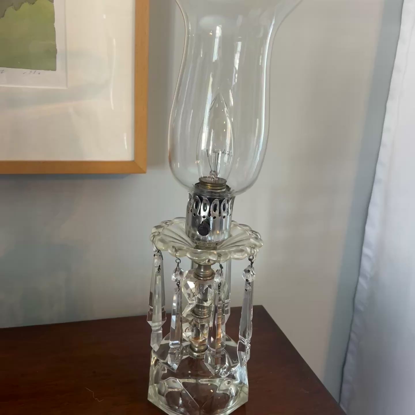 video of Clear glass hurricane lamp with a visible light bulb inside on a neutral background