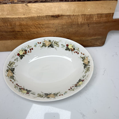 Decorative plate with floral patterns on a white surface with a wooden cutting board in the background