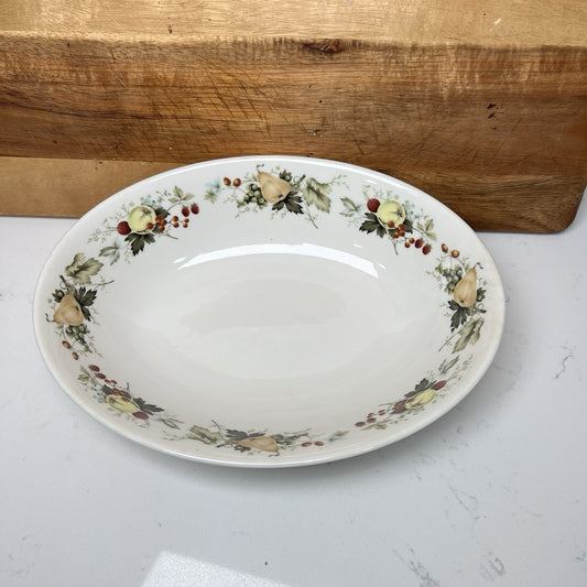 Decorative ceramic plate with floral and fruit design on a light surface.