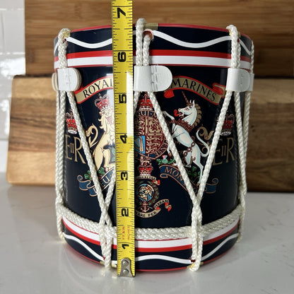 Decorative container with rope handles and a measuring tape for scale on a wooden surface.