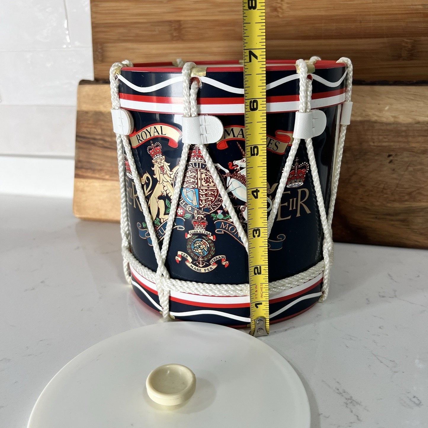 Decorative drum ice bucket with a tape measure for scale on a white surface.