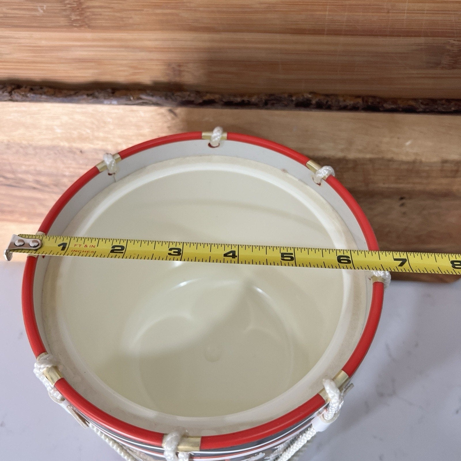 Measurement of a drum ice bucket  with a tape measure against a wooden background