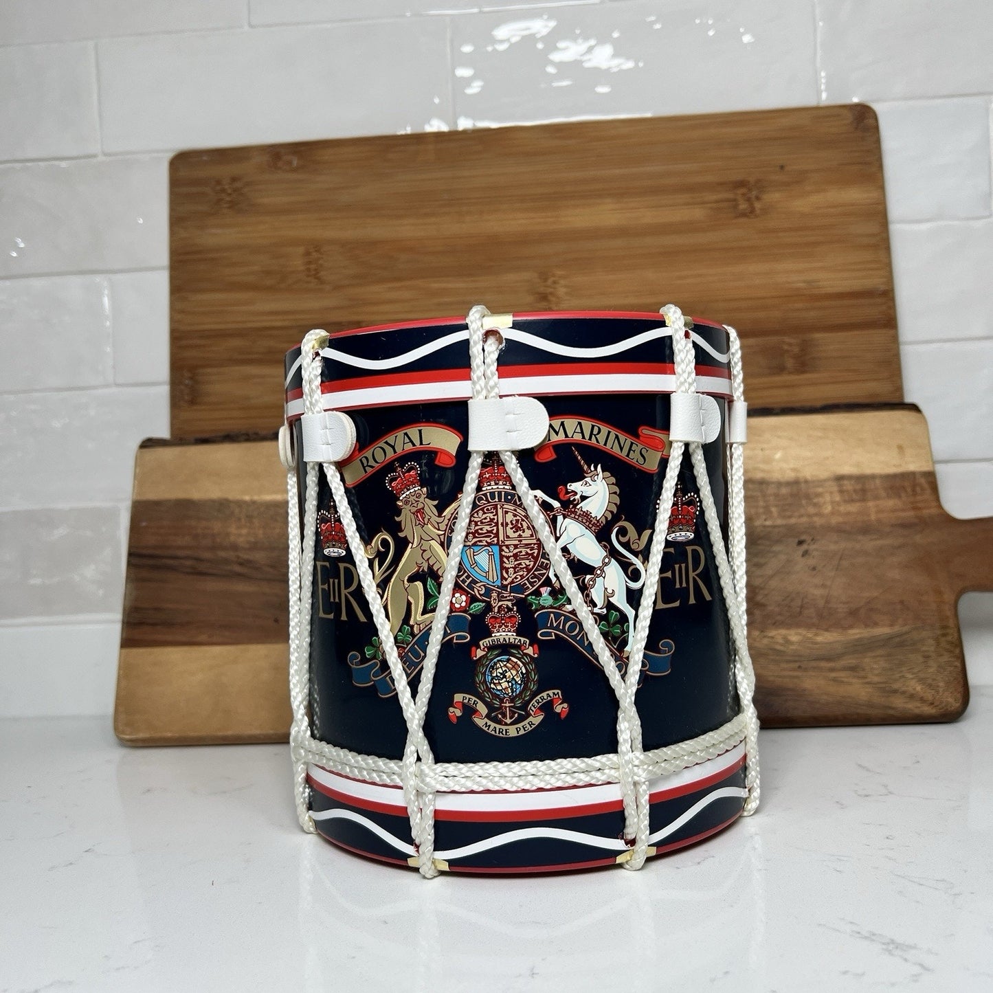 Decorative drum with ropes on a white surface with a wooden board in the background