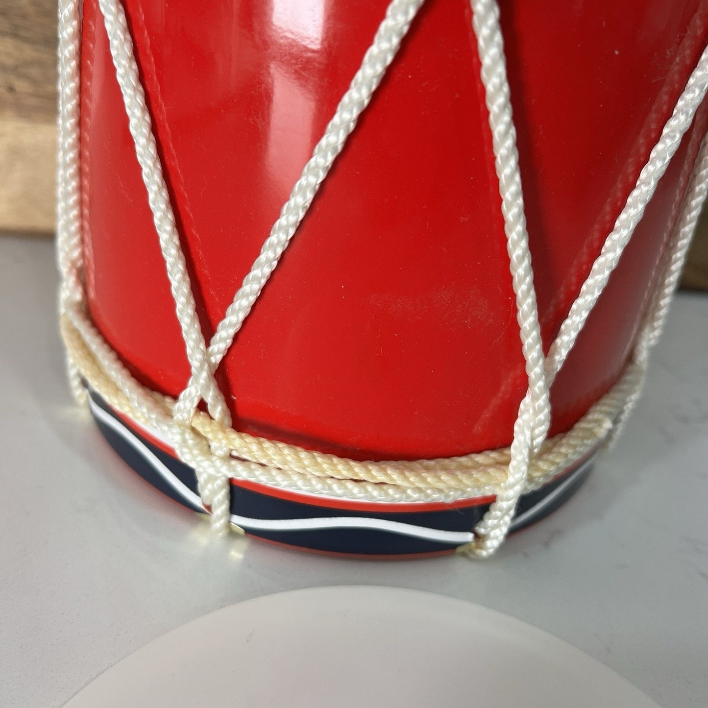 Close-up of a red drum with white strings on a light gray background