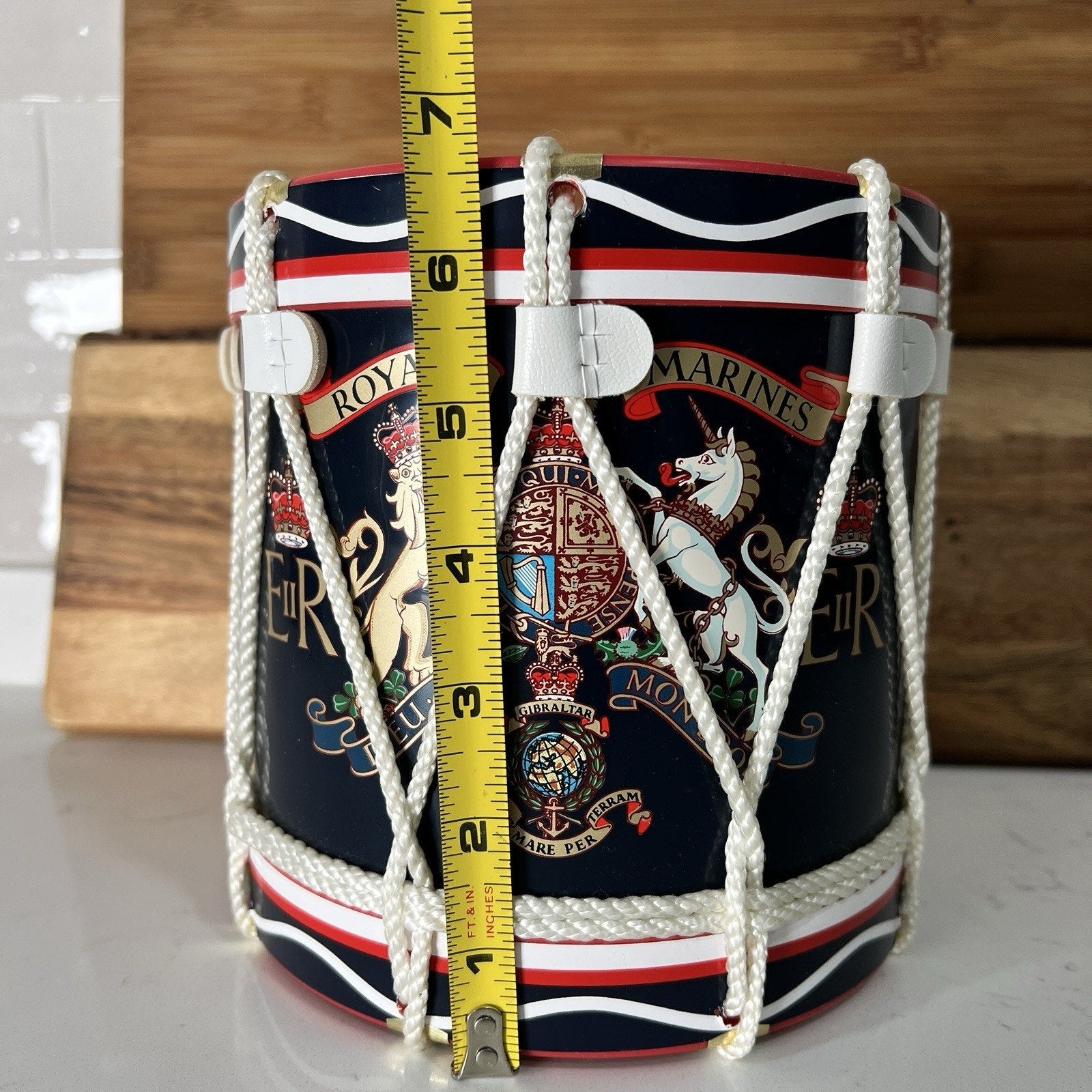 Decorative drum ice bucket 
with embroidered designs and a measuring tape for scale on a wooden background