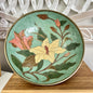 Decorative brass bowl with floral design on a wooden stand