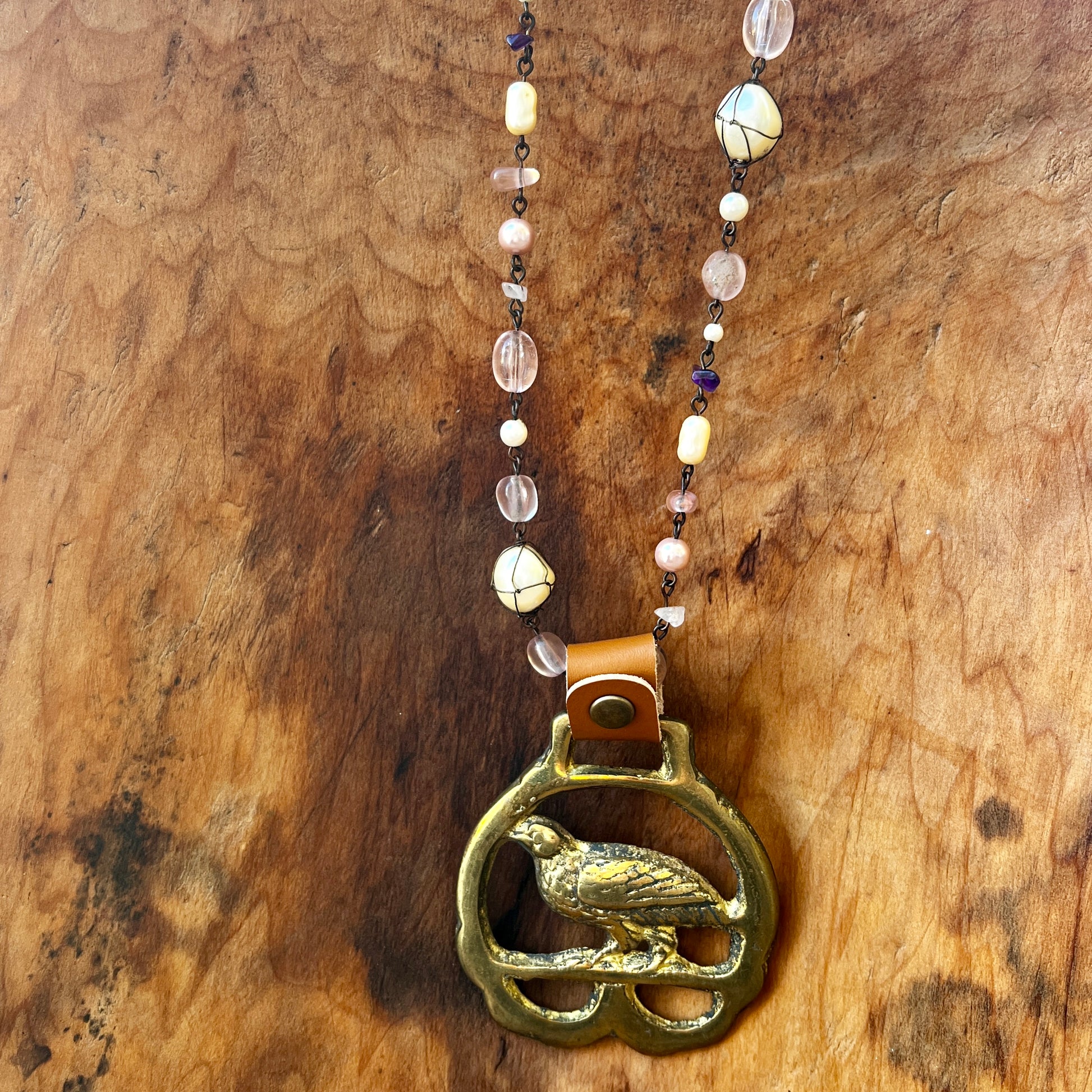 Necklace with a brass pendant of a bird on a wooden surface