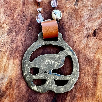 Metallic pendant with leather strap on a wooden surface