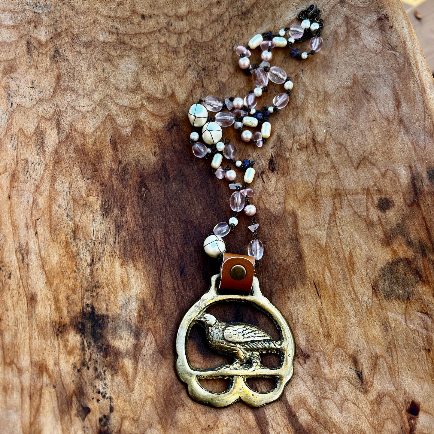 Necklace with a bird pendant and beaded chain on a wooden surface