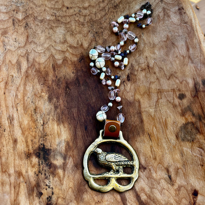 Necklace with a bird pendant and beaded chain on a wooden surface