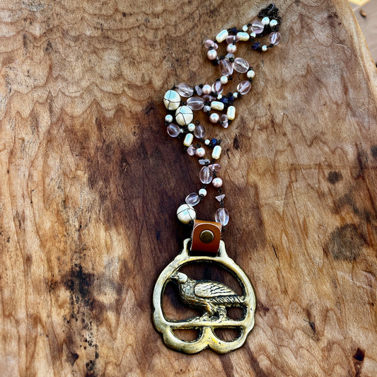Necklace with a bird pendant and beaded chain on a wooden surface